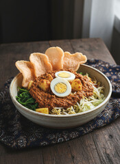Gado Gado Indonesian Salad with Peanut Sauce, Boiled Eggs, and Crackers on Wooden Table