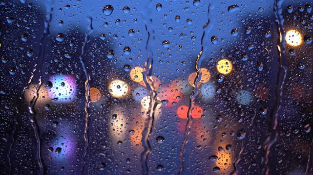 Raindrops on glass window with soft city light reflection