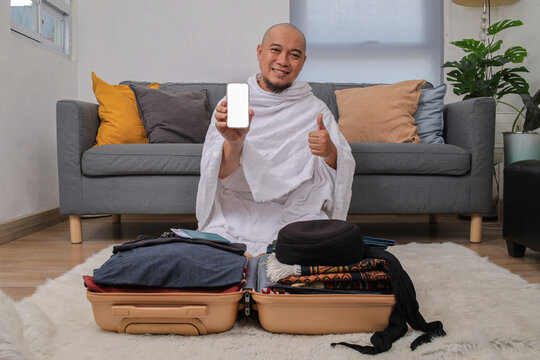 Asian Muslim Man in Ihram Clothes Showing Blank Phone Screen and Thumbs up