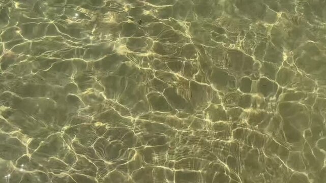 Abstract ocean water background captured from above in the Andaman Sea, Thailand. Sunlit transparent surface with gentle ripples creates a clean minimal water texture for graphic design and visual pro