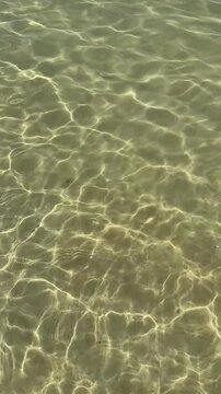 Abstract ocean water background captured from above in the Andaman Sea, Thailand. Sunlit transparent surface with gentle ripples creates a clean minimal water texture for graphic design and visual pro