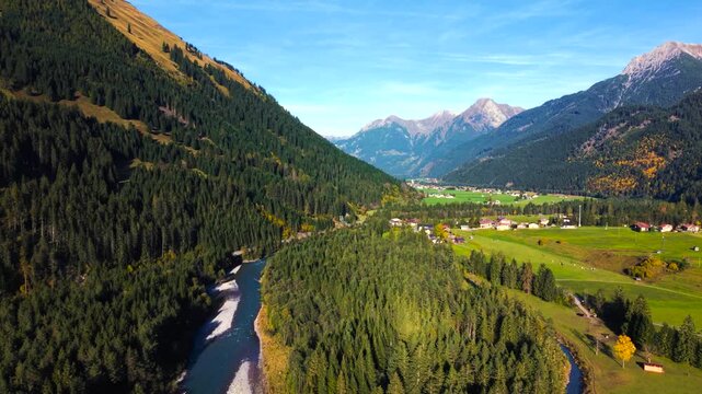 Golden autumn light over Lechtal valley with blue Lech river, forests and Alpine mountains, aerial view
