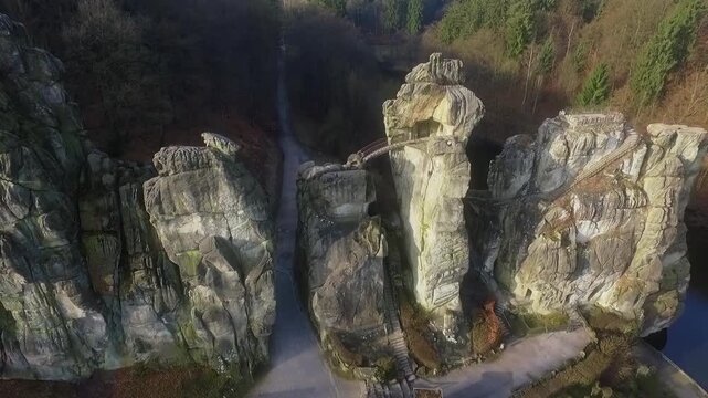 Drone ascends and tilts up over Externsteine rocks, revealing water and forest