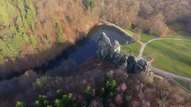 Drone advances and tilts down above Externsteine surrounded by autumn forest