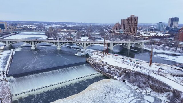 Minneapolis cityscape with a frozen Mississippi river, St Anthony Falls and snowy urban landscape