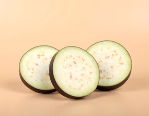 Three sliced eggplants, circular, against a pale orange backdrop
