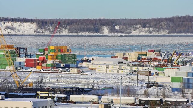 Winter view of industrial harbor of Anchorage, Alaska, cargo containers, industrial cranes, frozen shoreline and maritime infrastructure. A northen harbor operating in harsh Arctic conditions. 