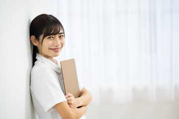 Side View of Smiling Young Woman in White Uniform Holding Clipboard
