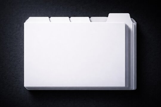 Top view of blank white index tab dividers stacked on a dark textured surface. Office organization concept with clean layout and copy space for labeling or branding.