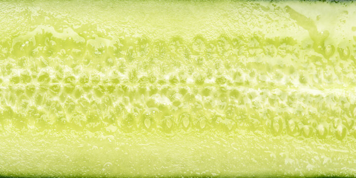 Macro of sliced cucumber with water droplets makes crisp green background with copy space for skincare, spa, or food ads.