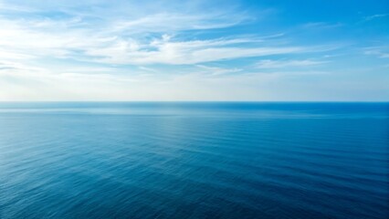 Fototapeta premium Expansive ocean horizon under a clear blue sky with wispy white clouds, serene and tranquil natural landscape.