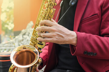 Obraz premium An elegant musician playing a golden saxophone outdoors. Close up.