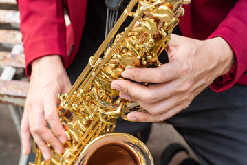 Obraz premium An elegant musician playing a golden saxophone outdoors. Close up.