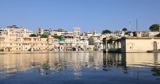 Buildings and ghats reflecting on the blue waters of lake pichola in Udaipur, Rajasthan, India.