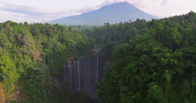 Aerial View of Tumpak Sewu Waterfall with Mount Semeru Volcano in the Distance, East Java, Indonesia