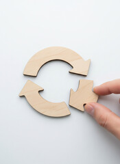 Recycling Symbol Puzzle Piece Being Placed by Hand on White Background
