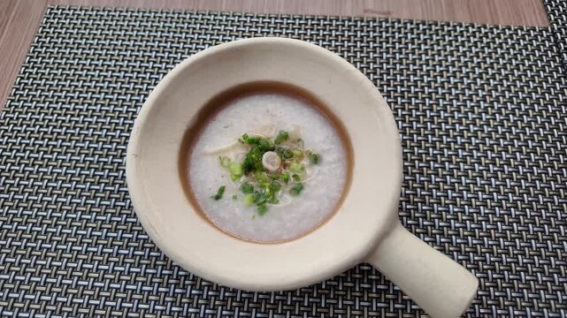 Overhead camera shot of rice porridge in bowl on placemat
