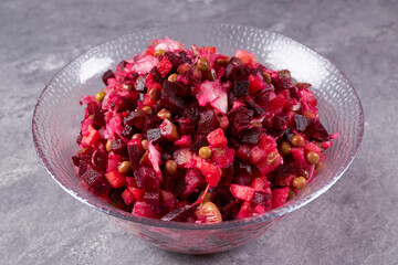A vinaigrette salad of beets, carrots, potatoes and green peas is on the table in a plate.
