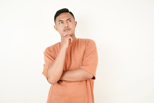 Portrait Indonesian Man Thinking and Posing Against White Background Wearing Orange Shirt