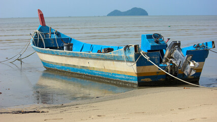 Obraz premium Blue and white traditional fishing boat on sandy beach in Malaysia