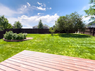 Fototapeta premium Backyard with wooden deck and green lawn