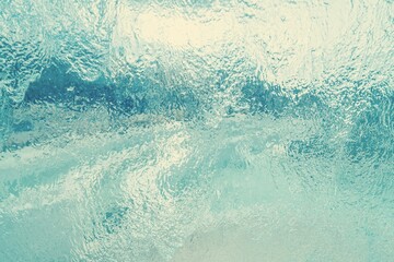 A stream of water running down a flat light turquoise glass surface