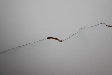 Crack in the wall near a home or building showing signs of damage and wear during the day