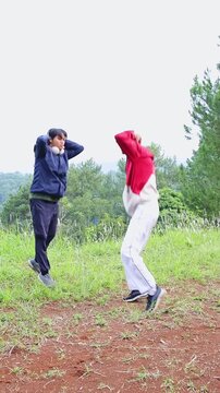 Athletic brothers practicing high-intensity vertical jumps and squats during fitness in nature