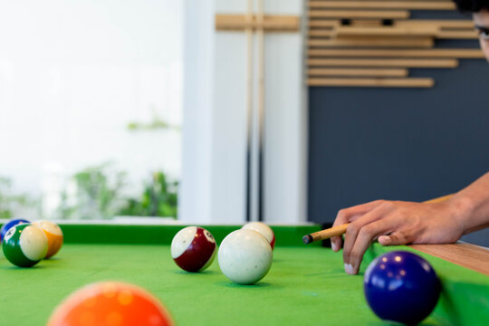 Man positioning cue stick toward cue ball on pool table, short-sleeve shirt, copy space