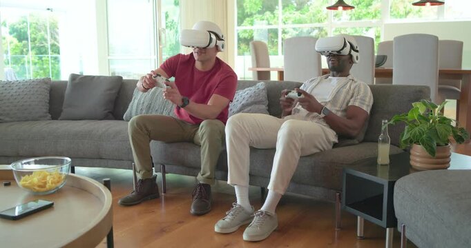 Diverse male friends placing white VR headsets and gripping white controllers on sofa playing game