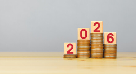 Rising stacked coins with 2026 on wooden block, copy space