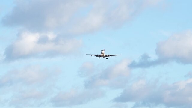 Plane landing at airport with clear skies and colorful clouds in the background