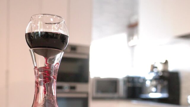 Red Wine Pouring Through Aerator Into Glass Decanter in Modern Kitchen