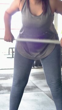 Vertical video: Tapping chalk, gym woman in tank adjusting stance, gripping barbell preparing lift