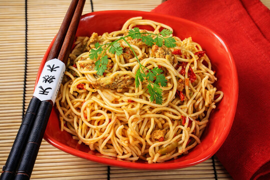 Nouilles asiatiques saut&eacute;es servies dans un bol rouge avec baguettes