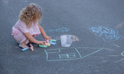 Naklejka premium Creative little girl drawing with colorful chalks on asphalt outdoors