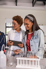 African american instructor guiding teenage students handling tubes with tongs and tablet