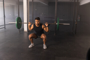 Male fitness enthusiast performing barbell back squat on rubber mats at gym weightlifting zone © wavebreak3