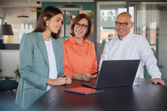 Business woman using laptop near colleagues at office