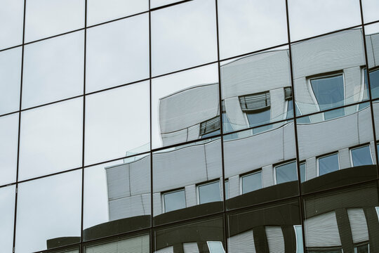 Abstract architecture glass facade with urban reflection pattern on modern building windows following curved roofline background texture
