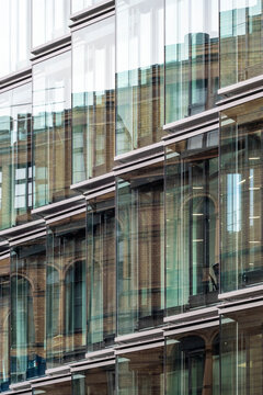 Abstract architecture glass facade with urban reflection pattern on modern building windows blending heritage brick details background texture