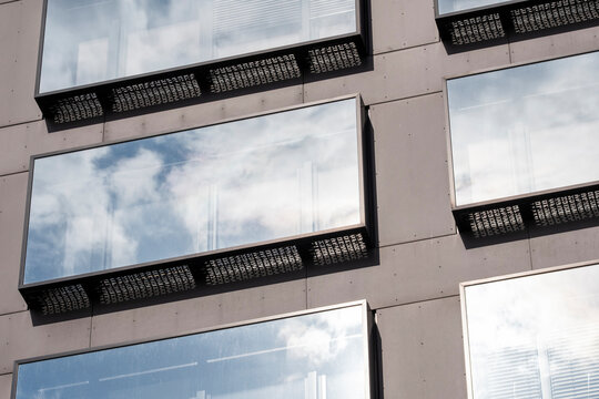 Abstract architecture glass facade with urban reflection pattern on modern building windows framing sky clouds and geometric background texture