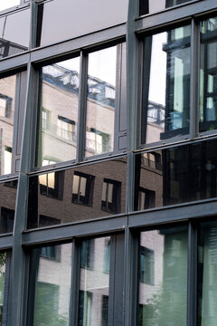 Abstract architecture glass facade with urban reflection pattern on modern building windows showing distorted neighboring buildings background texture