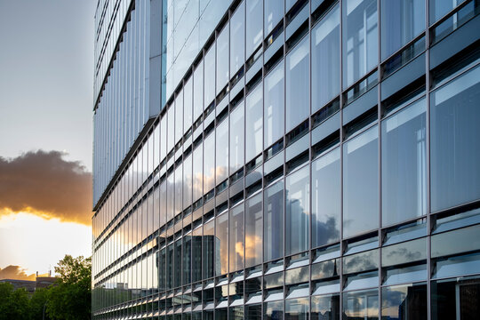 Abstract architecture glass facade at sunset with urban reflection pattern on modern building windows creating geometric design background texture