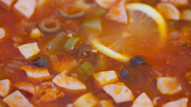 Closeup view of flavorful smokey meat stew with olives and vegetables, Rustic homestyle bowl showcasing delicious smoky meat soup with vegetables and lemon slice