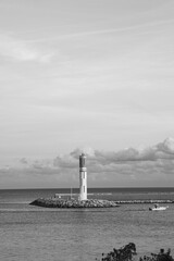 Fototapeta premium White and red lighthouse on a rocky pier at the entrance to Port Vauban in Antibes, French Riviera, France