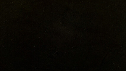 closeup black corduroy fabric texture with white lint fibers and subtle dust specks in dim moody lighting evoking mysterious abstract pattern