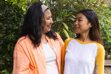 Obraz premium Diverse mother and daughter smiling together in backyard with patterned headband on mother