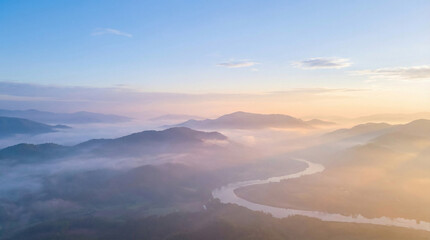 Mountain and river landscape with morning mist and soft light creating a tranquil atmosphere.