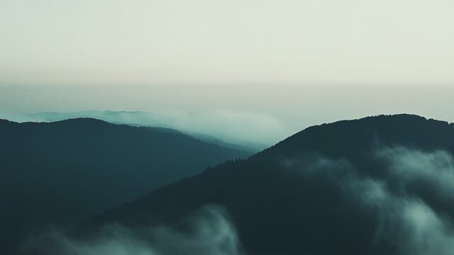 Distant mountain ridges emerge above a vast sea of morning fog, soft light casting blue green silhouettes across a serene, ethereal valley panorama perfect for travel or nature projects
